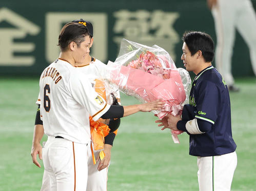 巨人対ヤクルト　1回裏巨人2死、プロ通算2000安打を達成した坂本（左）に花束を手渡すヤクルト山田哲（撮影・河野匠）