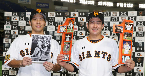 開幕から11連勝を達成した巨人菅野（右）は笑顔で記念撮影に納まる。左はスタルヒンの写真を手にする大城（2020年9月15日）