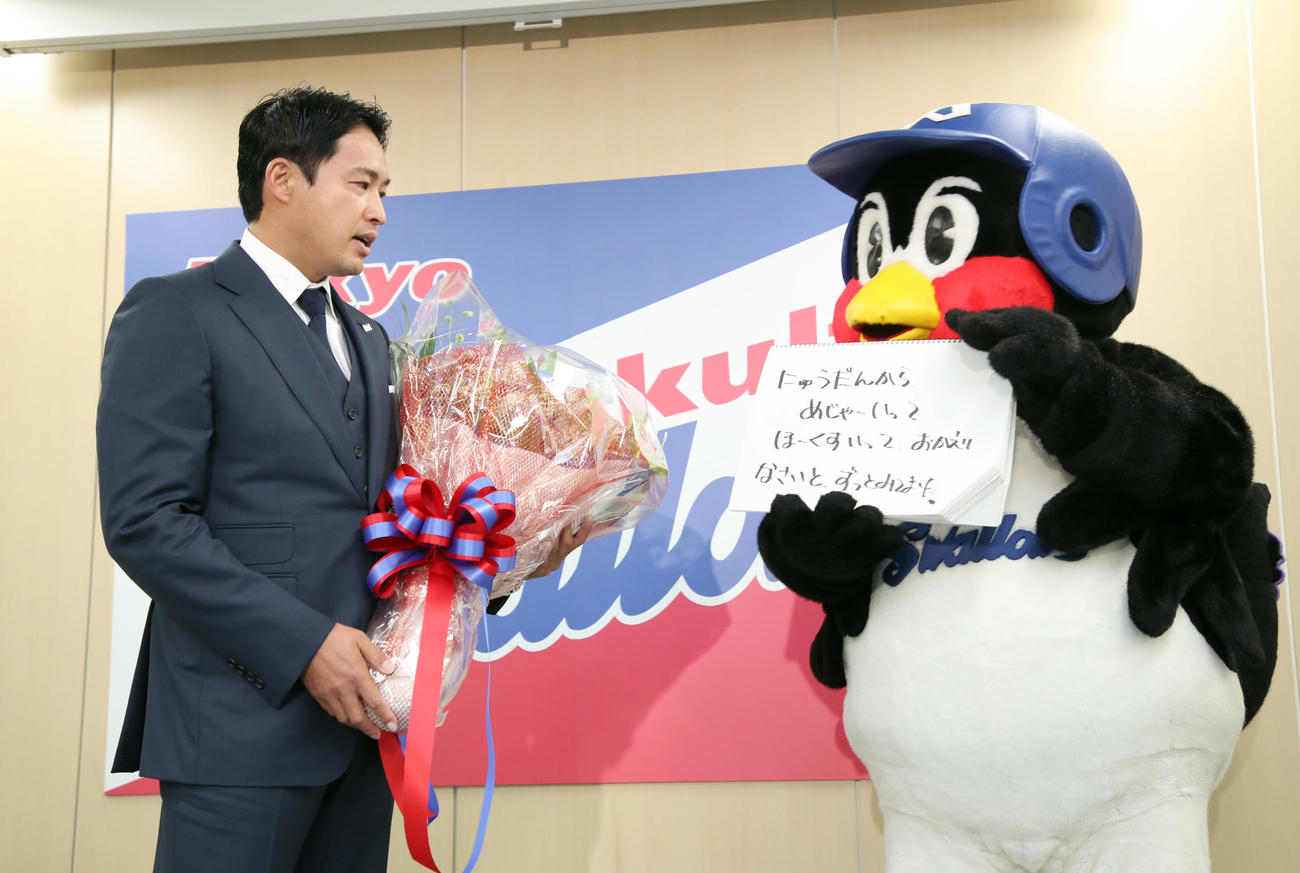 会見を行ったヤクルト五十嵐（左）に花束を渡しメッセージを送る球団マスコットのつば九郎（球団提供）