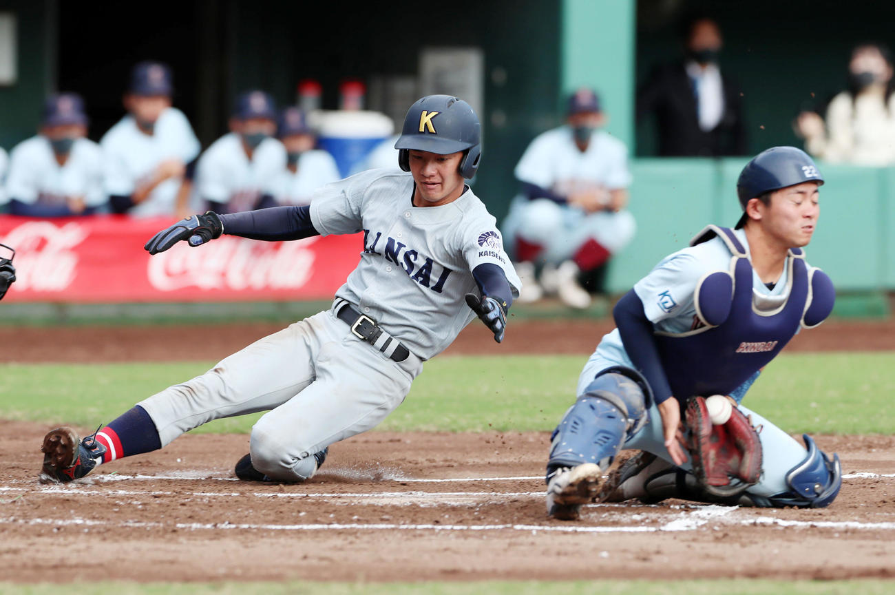 近大対関大　1回裏関大1死一、二塁、二走久保田有は野口の右前打で生還する、捕手井町（撮影・加藤哉）