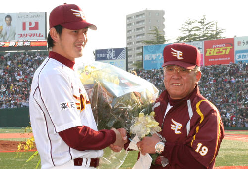 楽天岩隈久志選手会長（左）から通算1500勝を祝福する花束を受け取る楽天野村克也監督（2009年4月29日撮影）