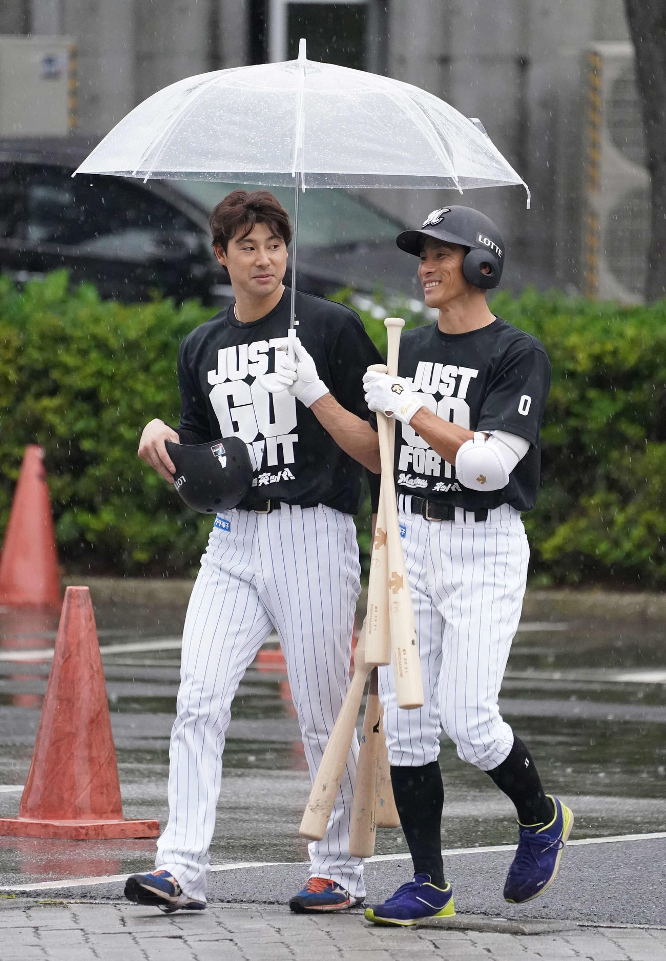練習を終え、荻野（右）の傘に入れてもらうロッテ藤岡（撮影・鈴木みどり）