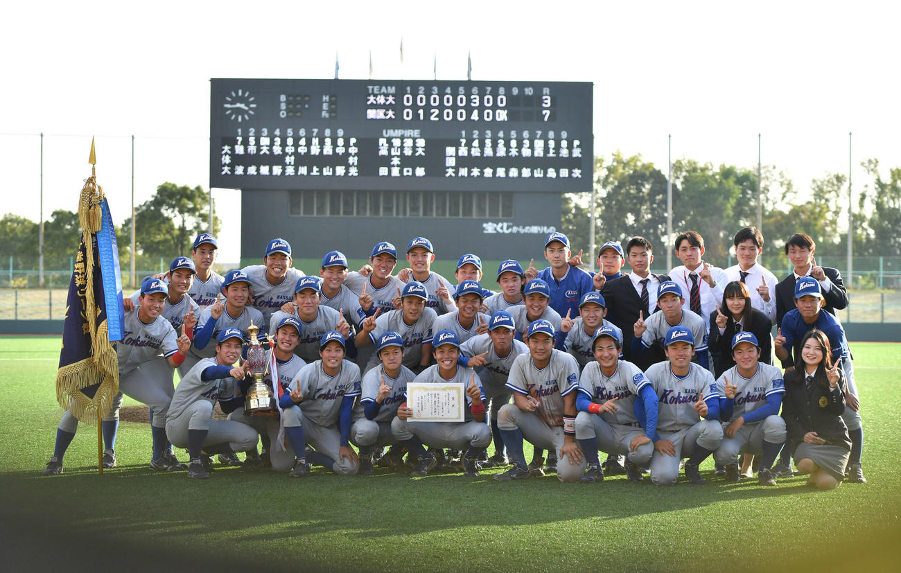 阪神大学野球優勝を決め、スコアボードを背に記念撮影する関西国際大ナイン（撮影・岩下翔太）