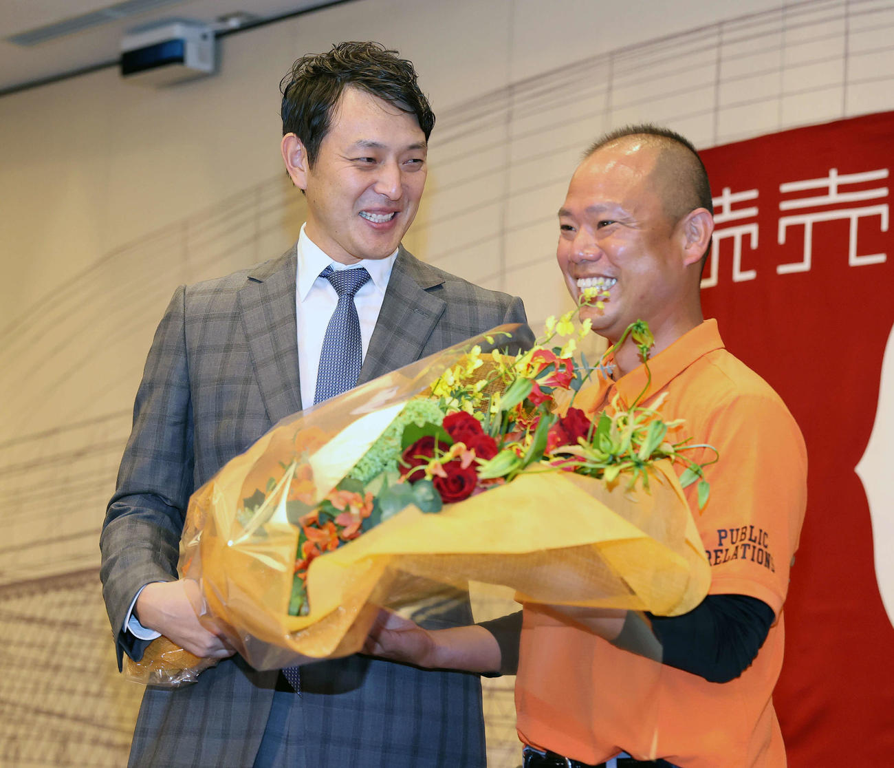 引退会見で元チームメイトの巨人朝井広報（右）と一緒に花束を持ち、笑顔を見せる岩隈（撮影・河野匠）