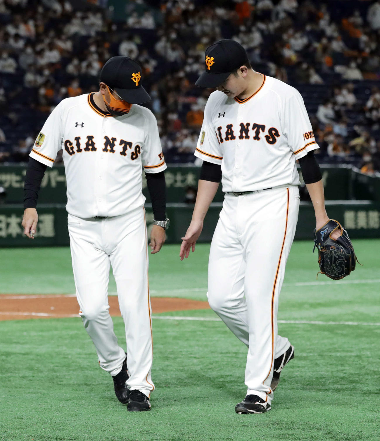 巨人対阪神　7回表、マウンドに上がった菅野（右）だが、右手を気にする様子を見せベンチにいったん引き揚げる。左は宮本コーチ（撮影・河野匠）