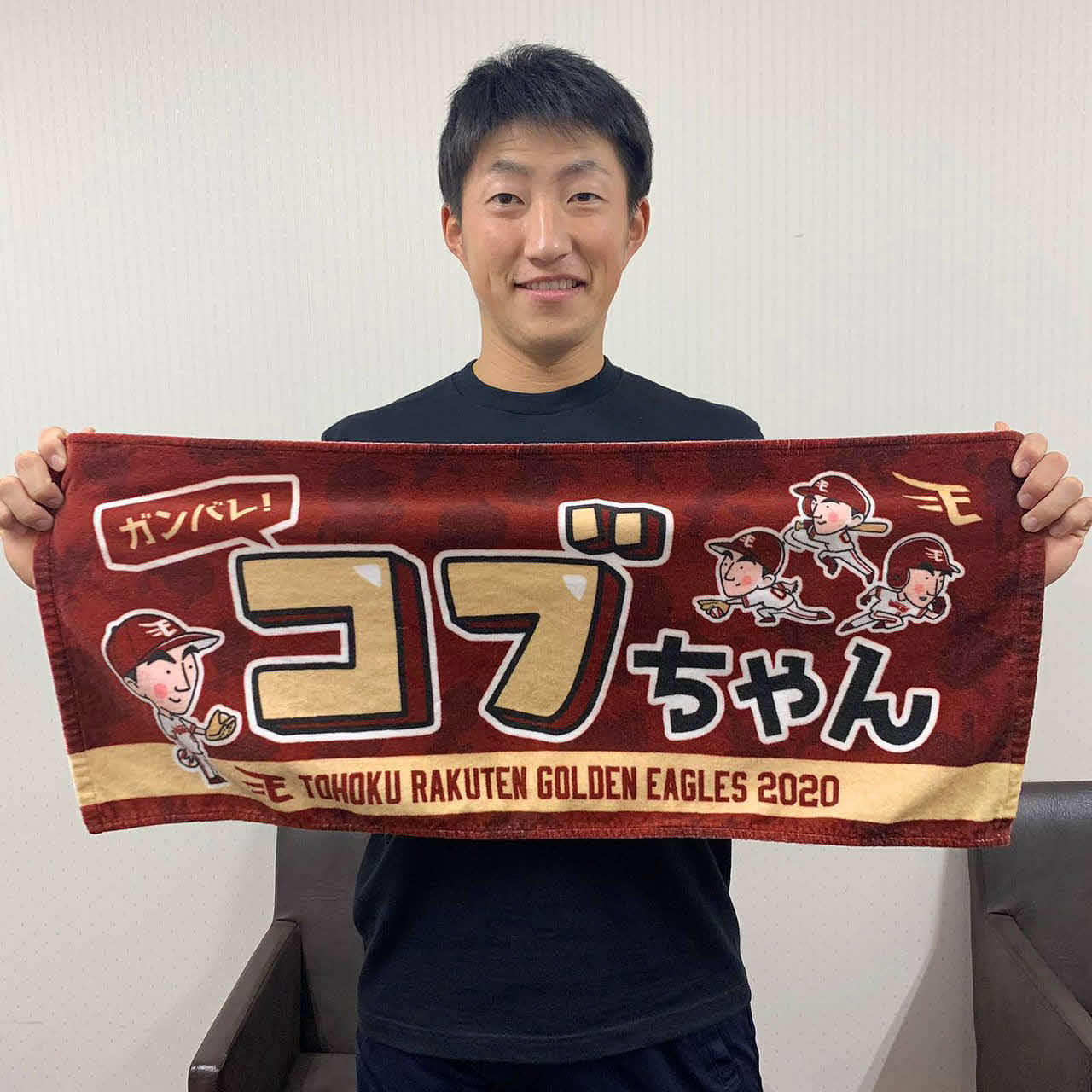 「ガンバレ！コブちゃん」とデザインされたタオルグッズを手にする楽天小深田（球団提供）