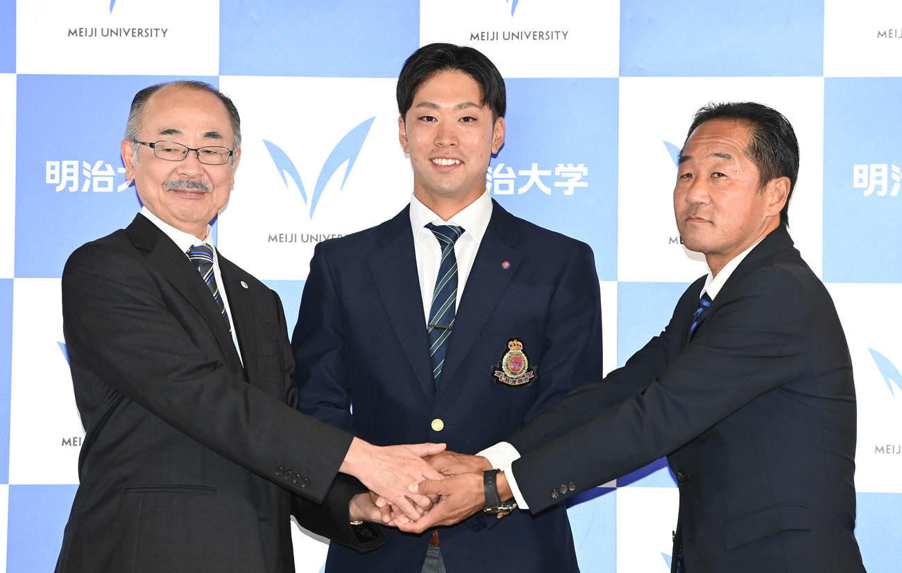 DeNAからドラフト1位指名を受けた明大・入江（中央）は田中硬式野球部監督（右）、井上部長と笑顔で握手（撮影・鈴木みどり）