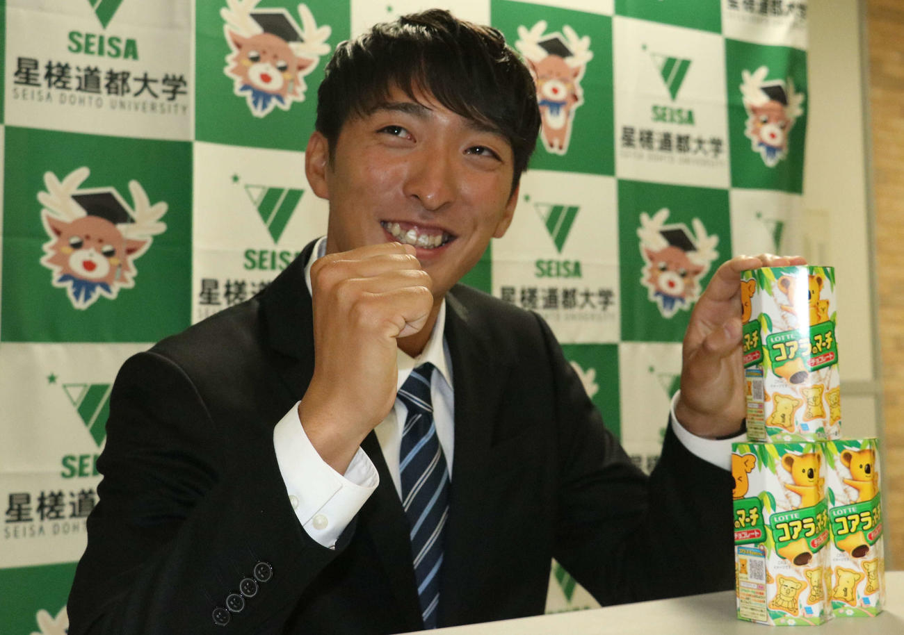 ロッテからドラフト4位指名を受け、お菓子を手に笑顔で活躍を誓う星槎道都大・河村（撮影・浅水友輝）