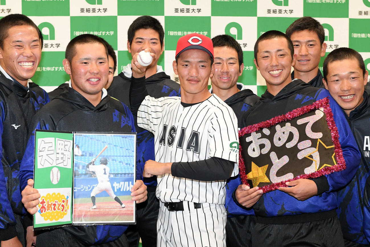 広島から6位指名された亜大・矢野は広島の帽子をかぶりポーズを決める（撮影・滝沢徹郎）