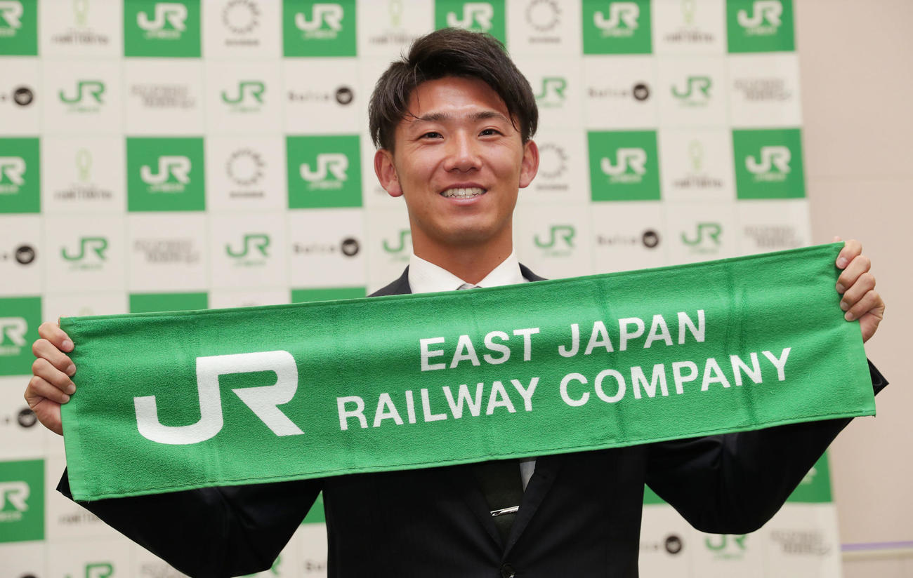 阪神から2位指名を受け笑顔でタオルを広げるJR東日本・伊藤（撮影・前田充）