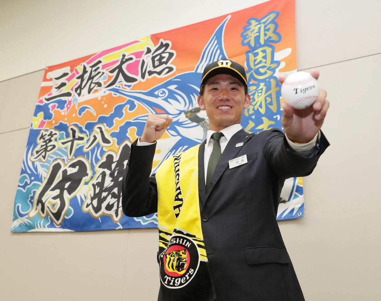 阪神から2位指名を受け、同僚から贈られた大漁旗の前で笑顔でポーズをとるJR東日本・伊藤（撮影・前田充）