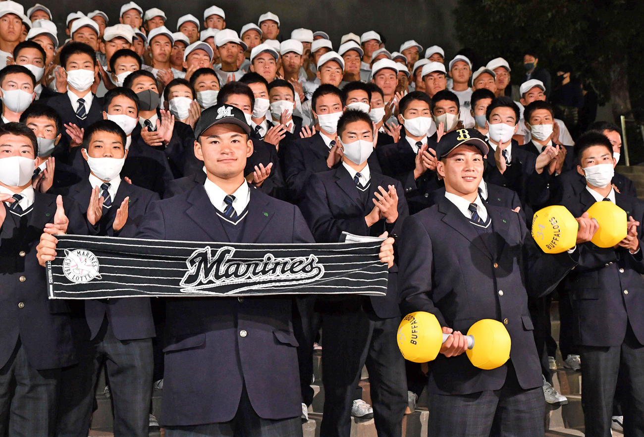 明石商からロッテに2位で指名された中森（左）とオリックス3位指名の来田は球団グッズを手に笑顔を見せる（撮影・岩下翔太）