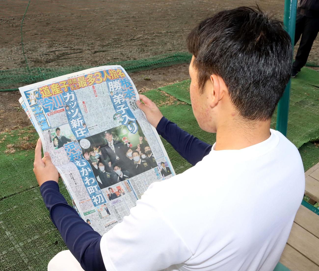 自身が指名されたことを報じる日刊スポーツ北海道版に目を通す苫小牧中央・根本投手（撮影・永野高輔）