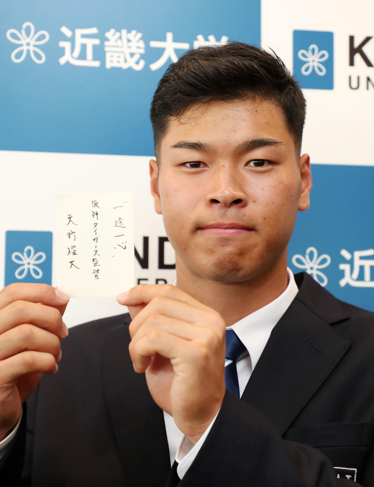 矢野監督のメッセージが書かれた交渉権獲得の札を披露する近大・佐藤輝（撮影・加藤哉）