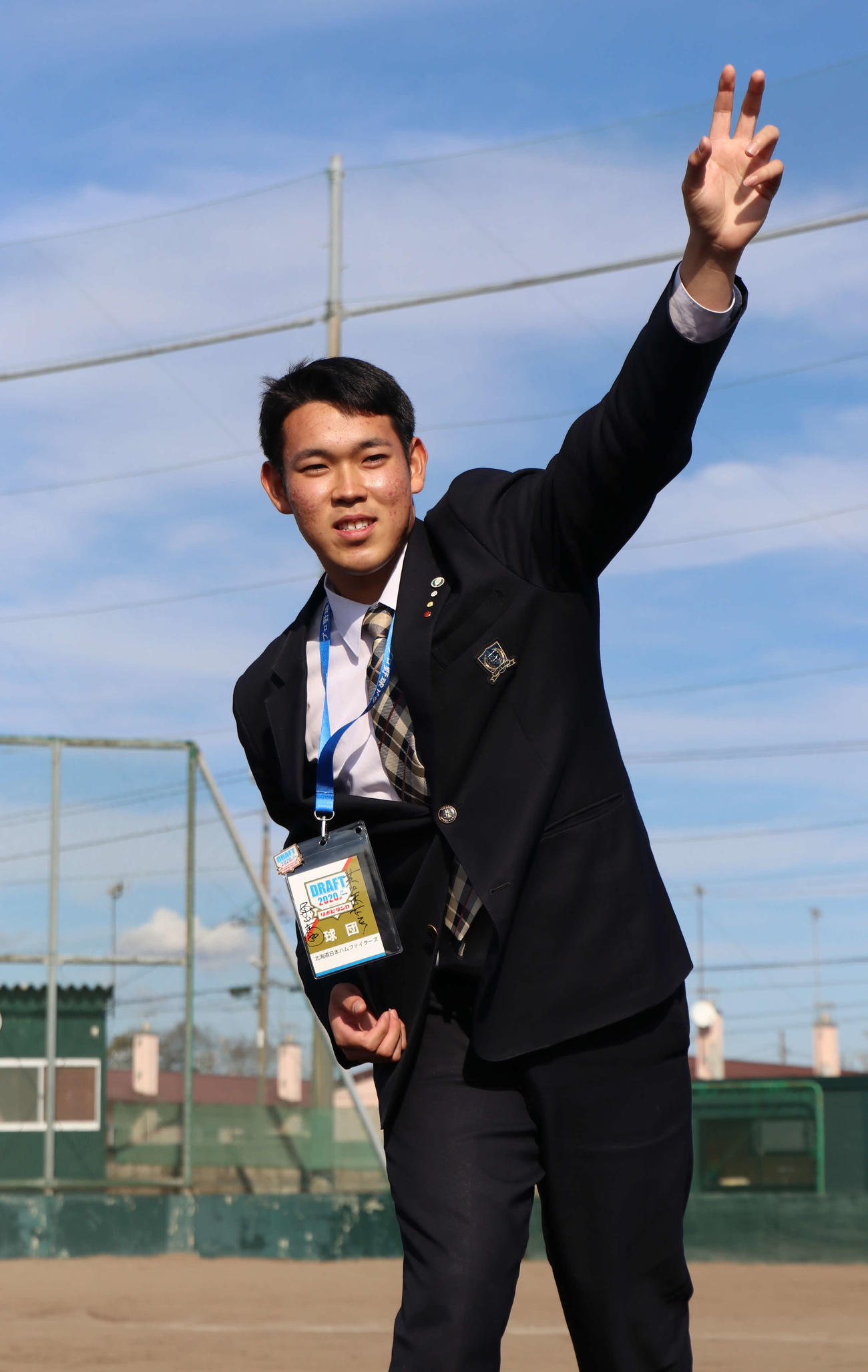 栗山監督の直筆サインが書かれたドラフト会議の入館証を首に掛け、グラウンドで投球ポーズをとる苫小牧中央・根本（撮影・山崎純一）