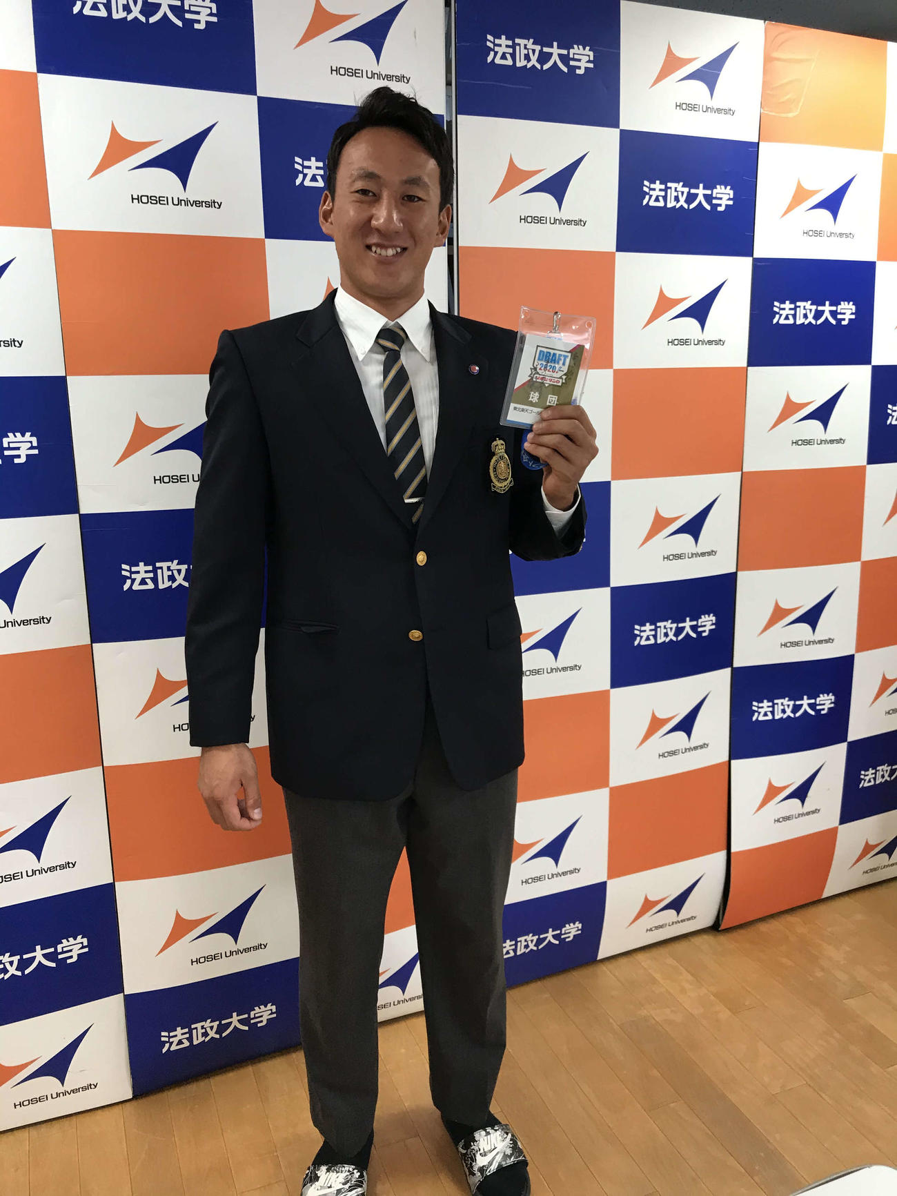 楽天ドラフト2位指名の法大・高田は担当スカウトから受け取った、三木監督のサイン入りのドラフト会議IDパスを手に笑顔を見せる（球団提供）