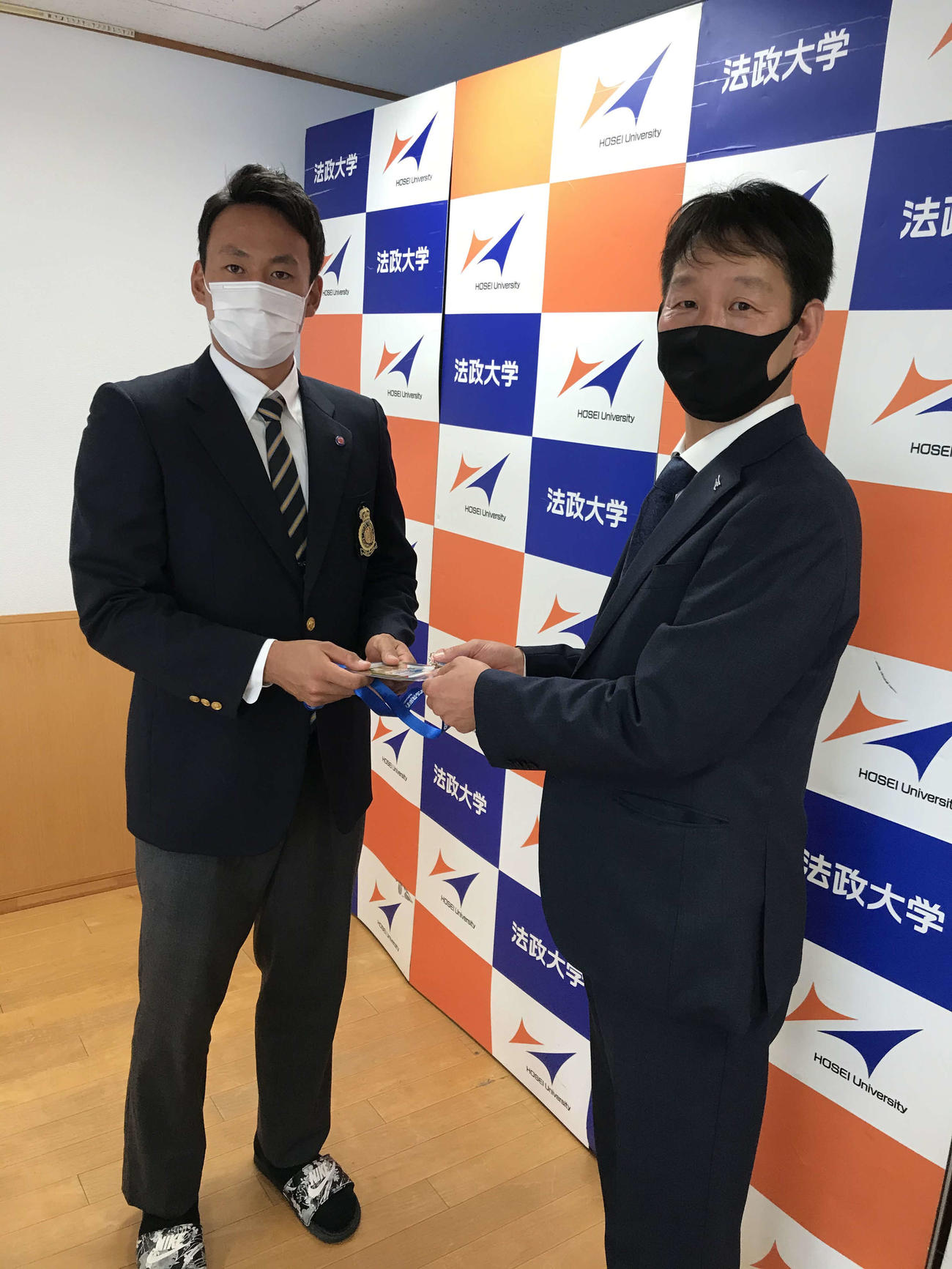 楽天ドラフト2位指名の法大・高田（左）は担当の部坂スカウト（右）からドラフト会議のIDパスを受け取る（球団提供）