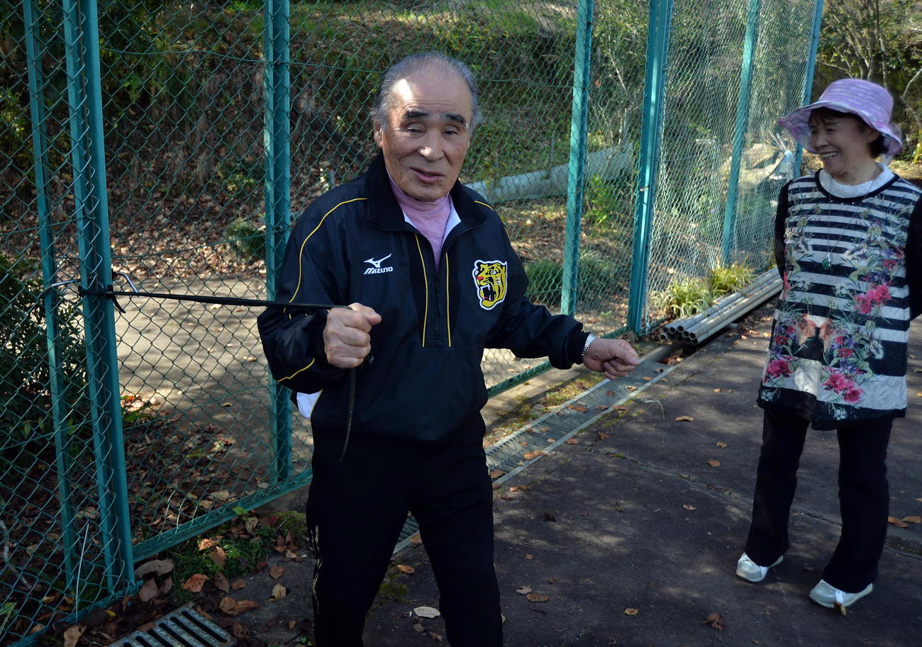 阪神ドラフト1位佐藤が体作りに利用したテニスコート横のゴムチューブを引っ張る祖父勲さん。右は祖母美智恵さん（撮影・中島正好）