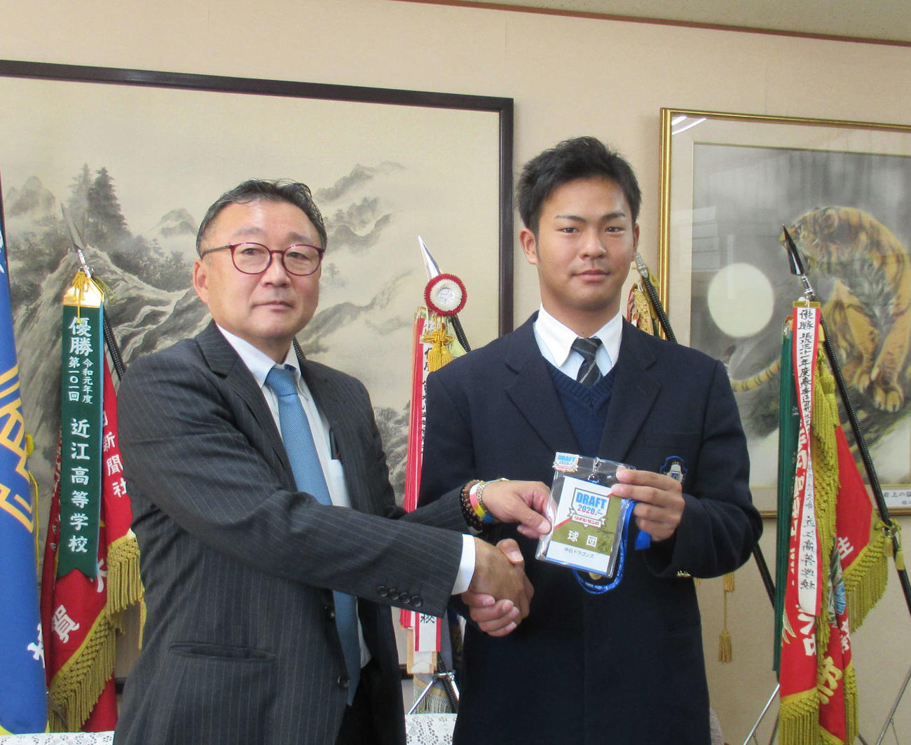 中日山本アマスカウトチーフ補佐からドラフト会議入館章を手渡されるドラフト3位、近江・土田龍空内野手