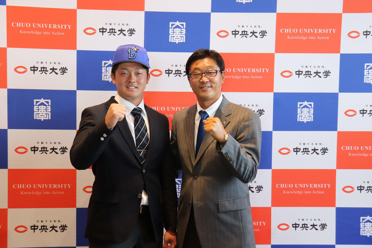 指名あいさつを受けたDeNAドラフト2位の中大・牧は担当スカウトの河原隆一スカウト部ディレクターとガッツポーズを見せる（撮影・保坂淑子）