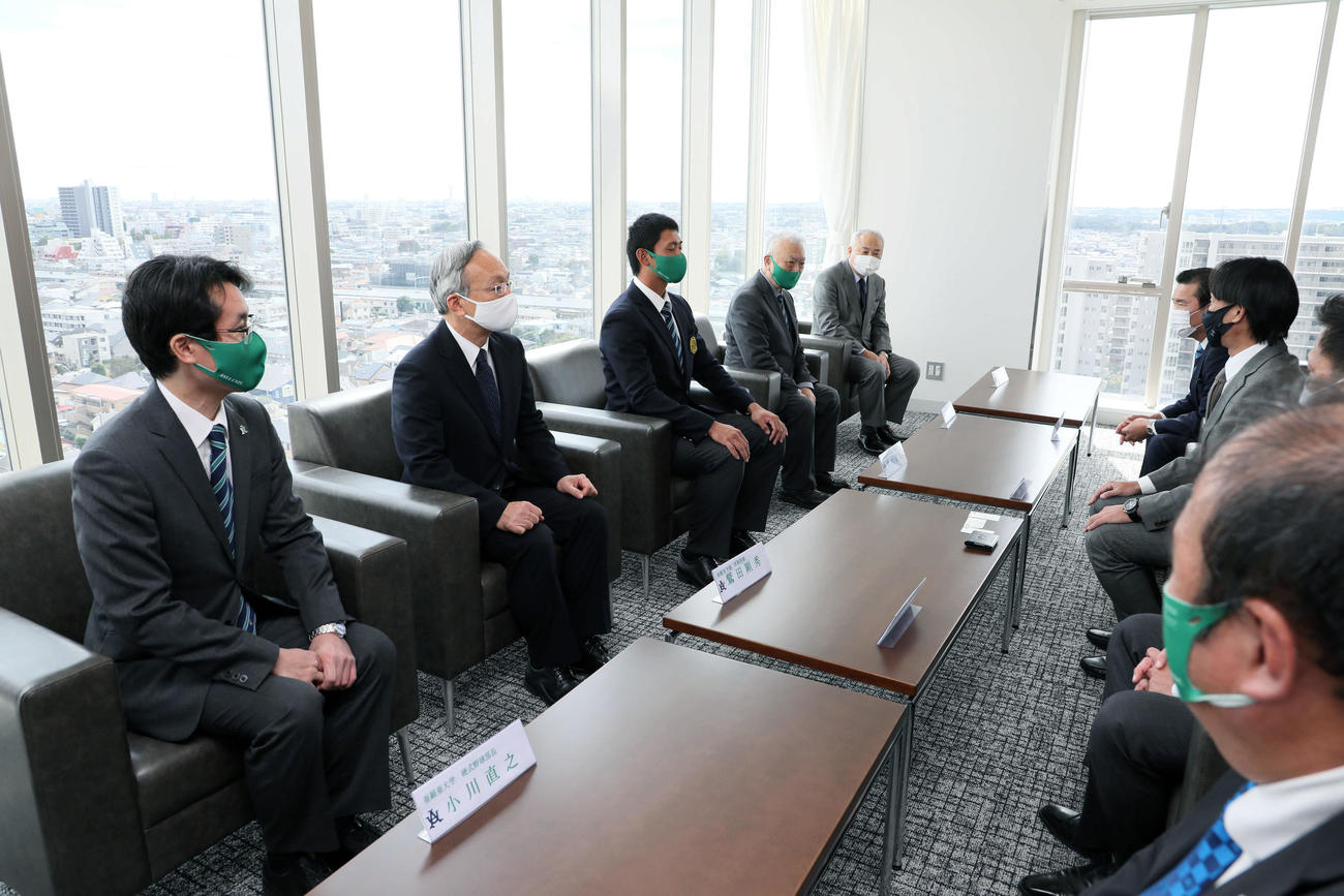 巨人大塚副代表（右奥）らから指名あいさつを受けるドラフト1位の亜大・平内（手前左から3人目）（代表撮影）