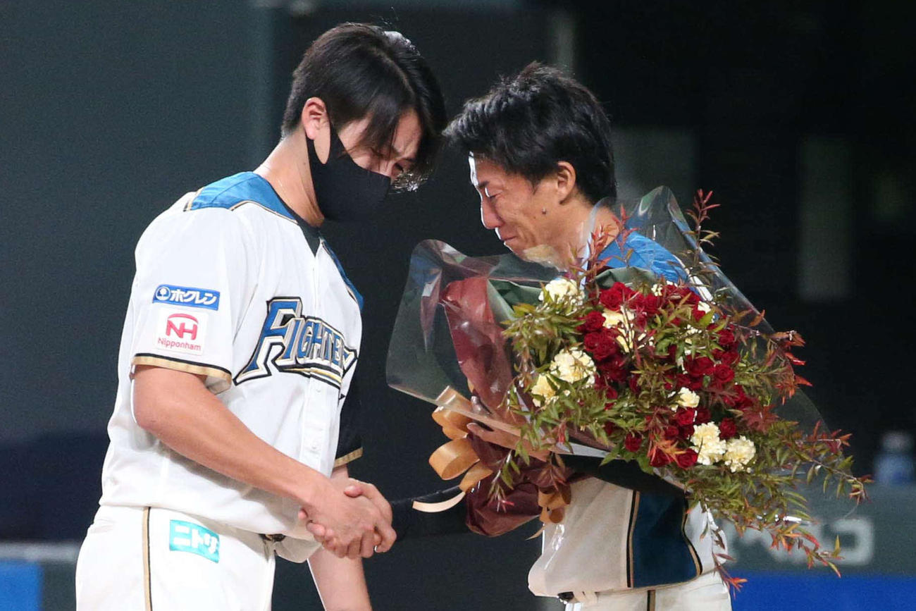 引退セレモニーで上沢（左）から花束を受け取る浦野（撮影・黒川智章）