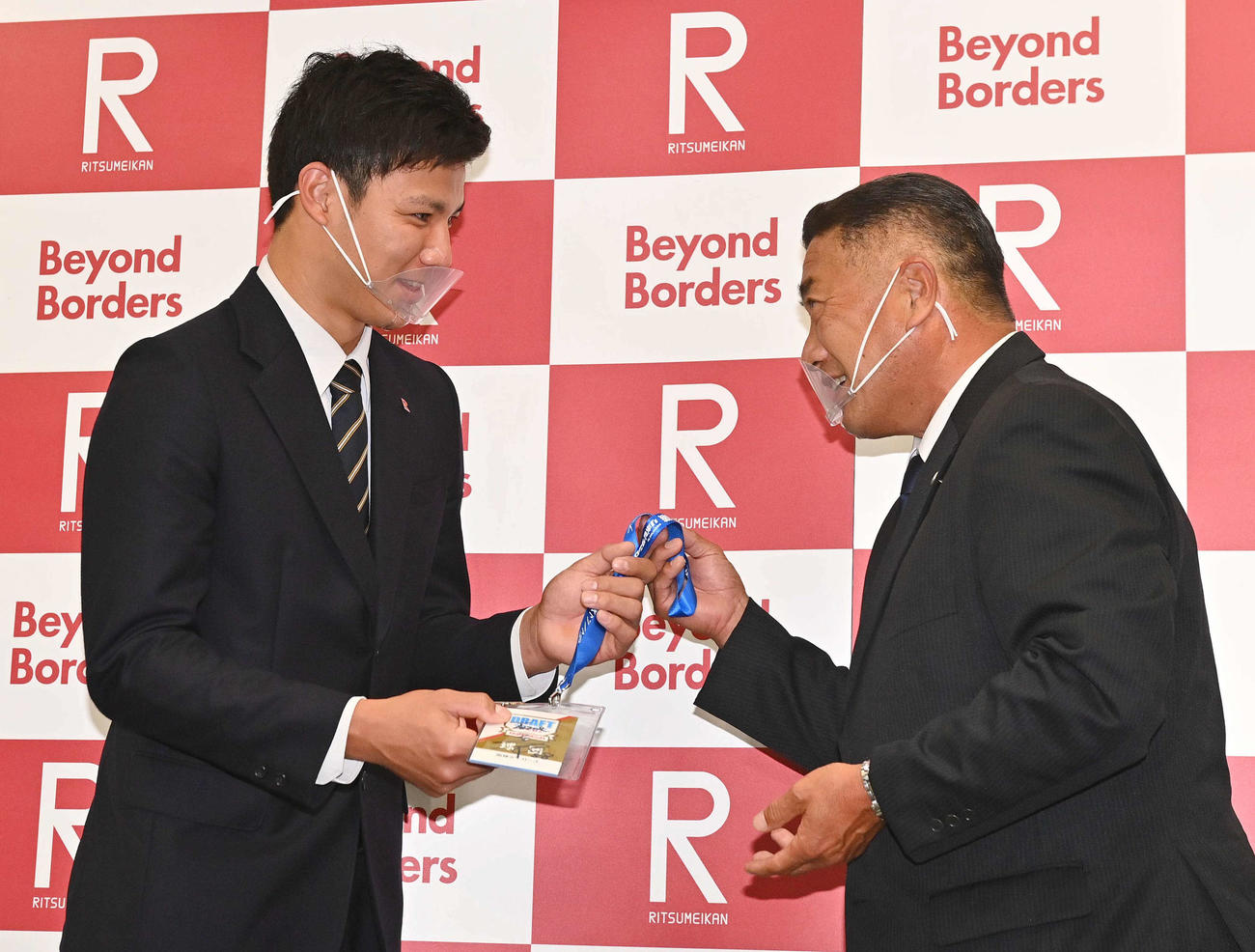 阪神・熊野輝光担当スカウト（右）から矢野燿大監督サイン入りのドラフト会議入館証を手渡されるドラフト4位指名を受けた立命大・栄枝裕貴（撮影・上田博志）