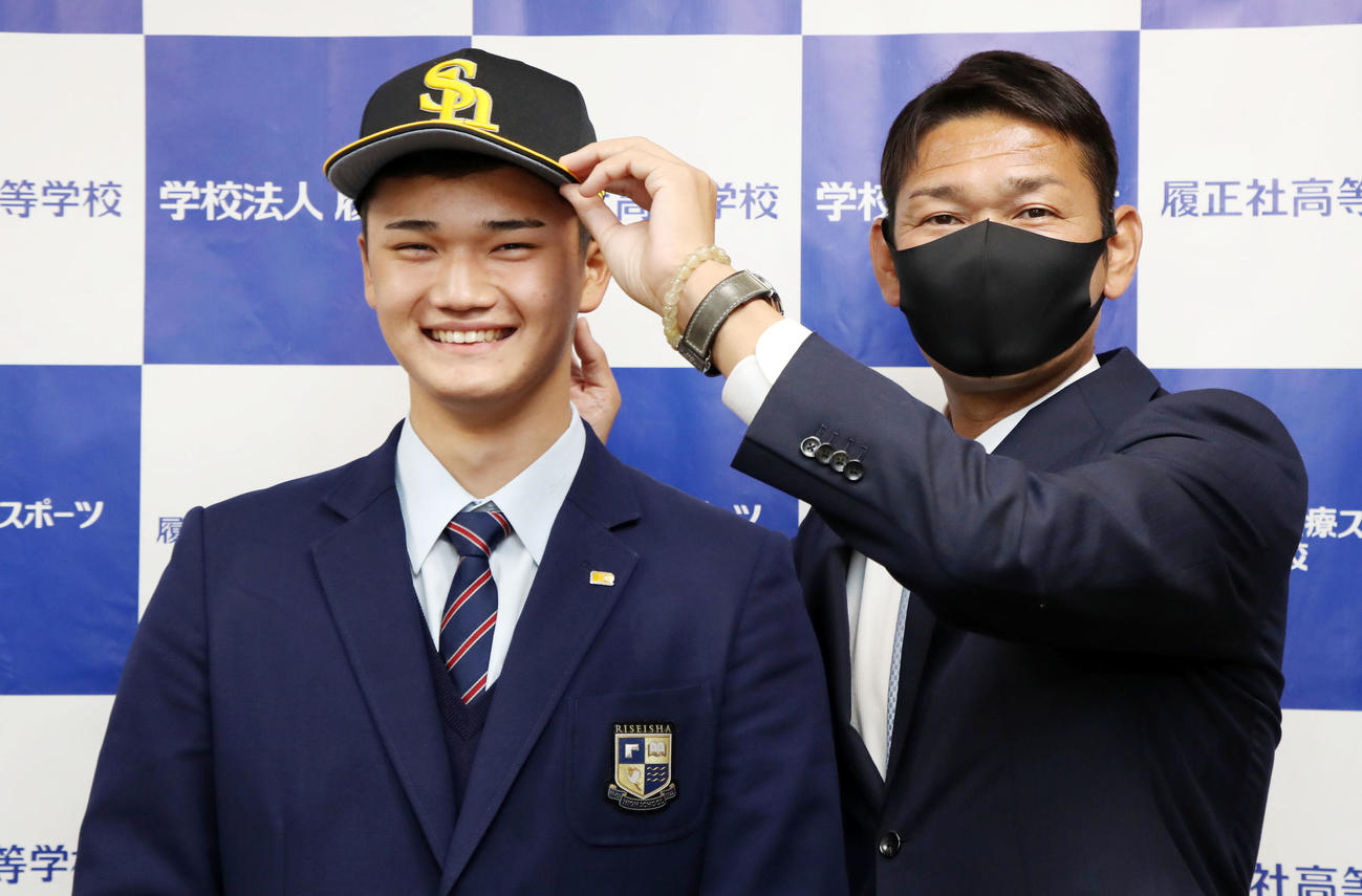 ソフトバンクから指名あいさつを受けた田上（左）は永井編成本部長から帽子をかぶせてもらう（撮影・加藤哉）