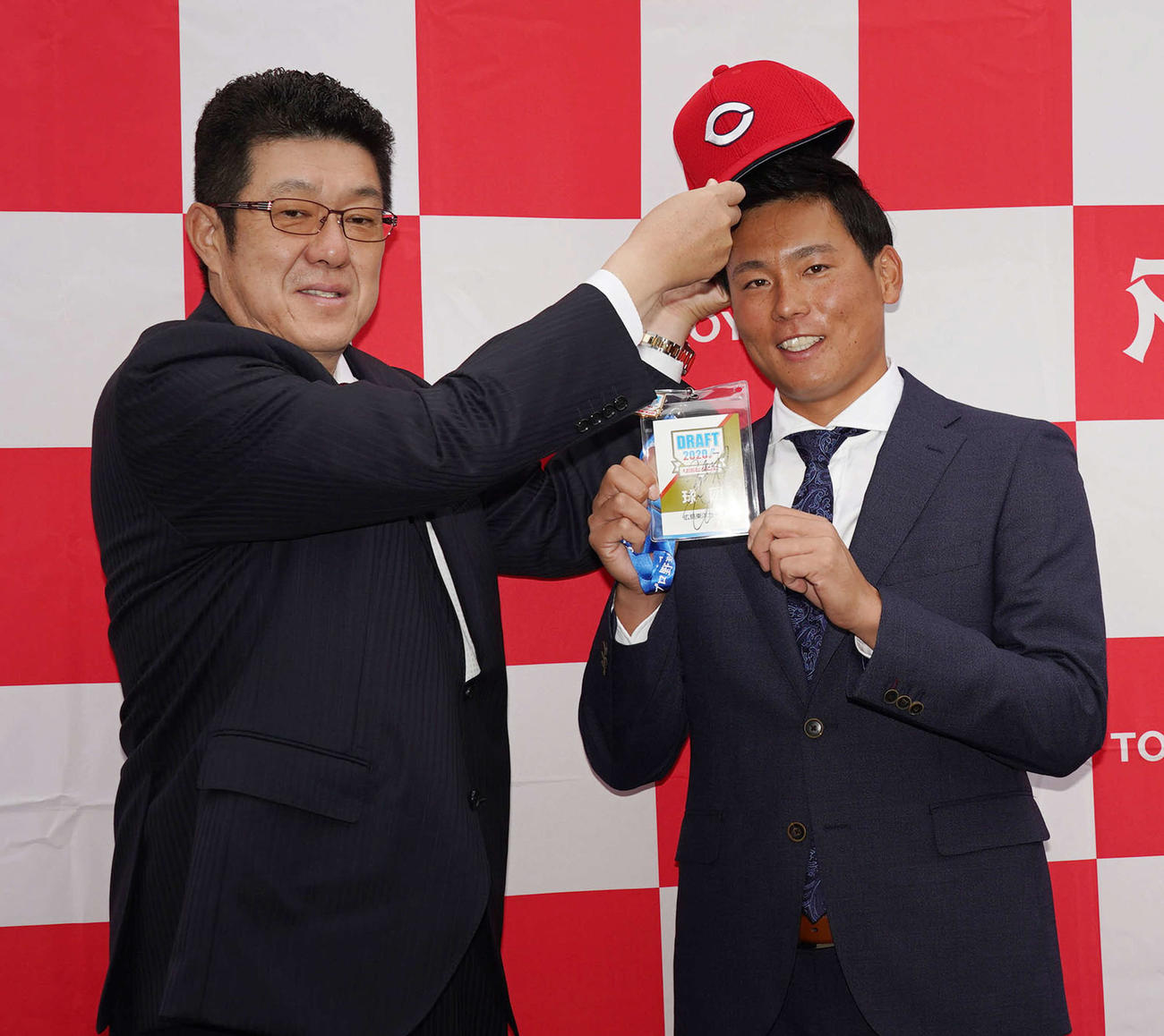 広島からドラフト1位指名され、初対面の佐々岡監督（左）から帽子をかぶらせてもらい笑顔を見せるトヨタ自動車・栗林（撮影・森本幸一）