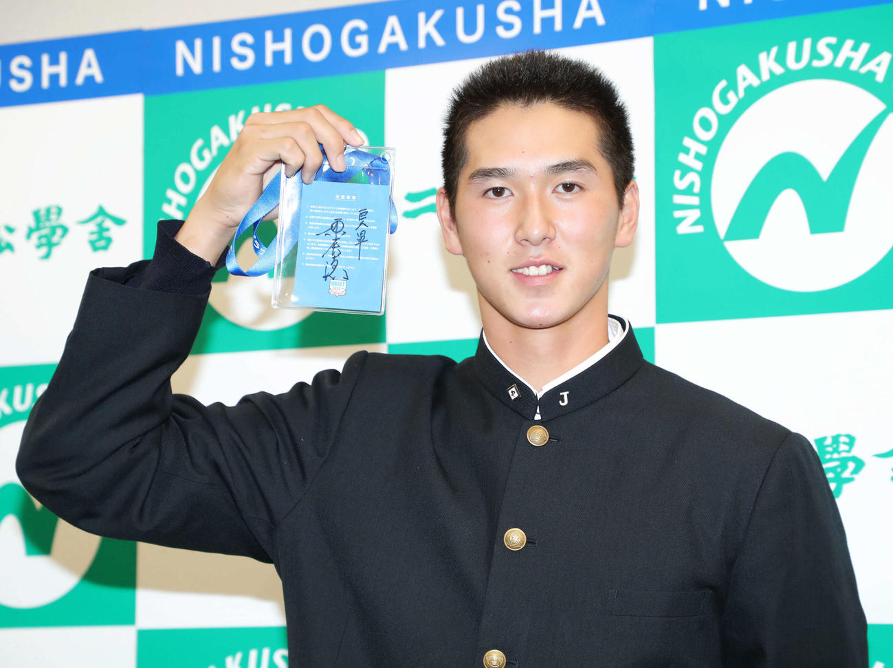 巨人原監督のサインが入ったドラフト会議のパスを手に、笑顔を見せる二松学舎大付・秋広（撮影・河田真司）