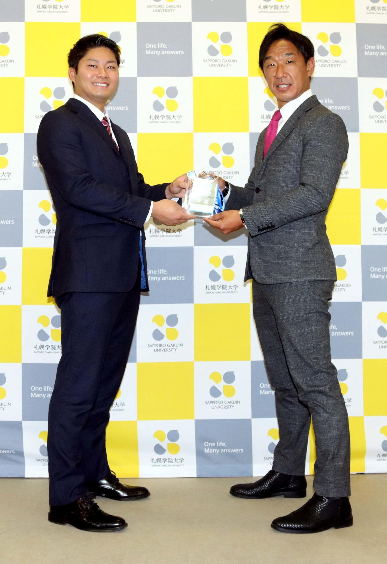 中日八木スカウトから与田監督のサインが入ったドラフト会議用パスを受け取る札幌学院大の近藤（左）（撮影・永野高輔）