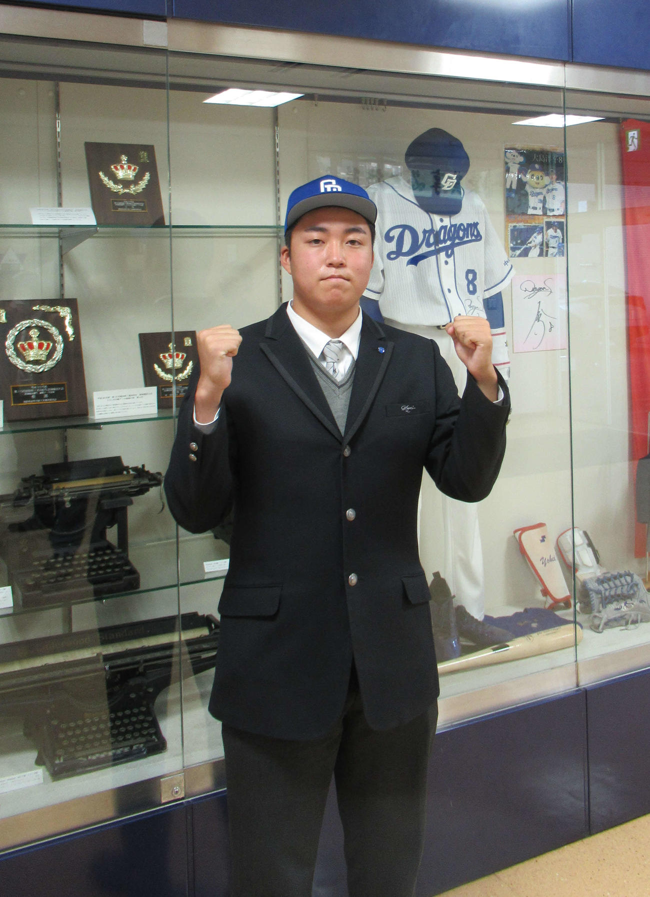 享栄の先輩、大島のユニホームの前でポーズを取る中日育成2位・上田洸太朗投手