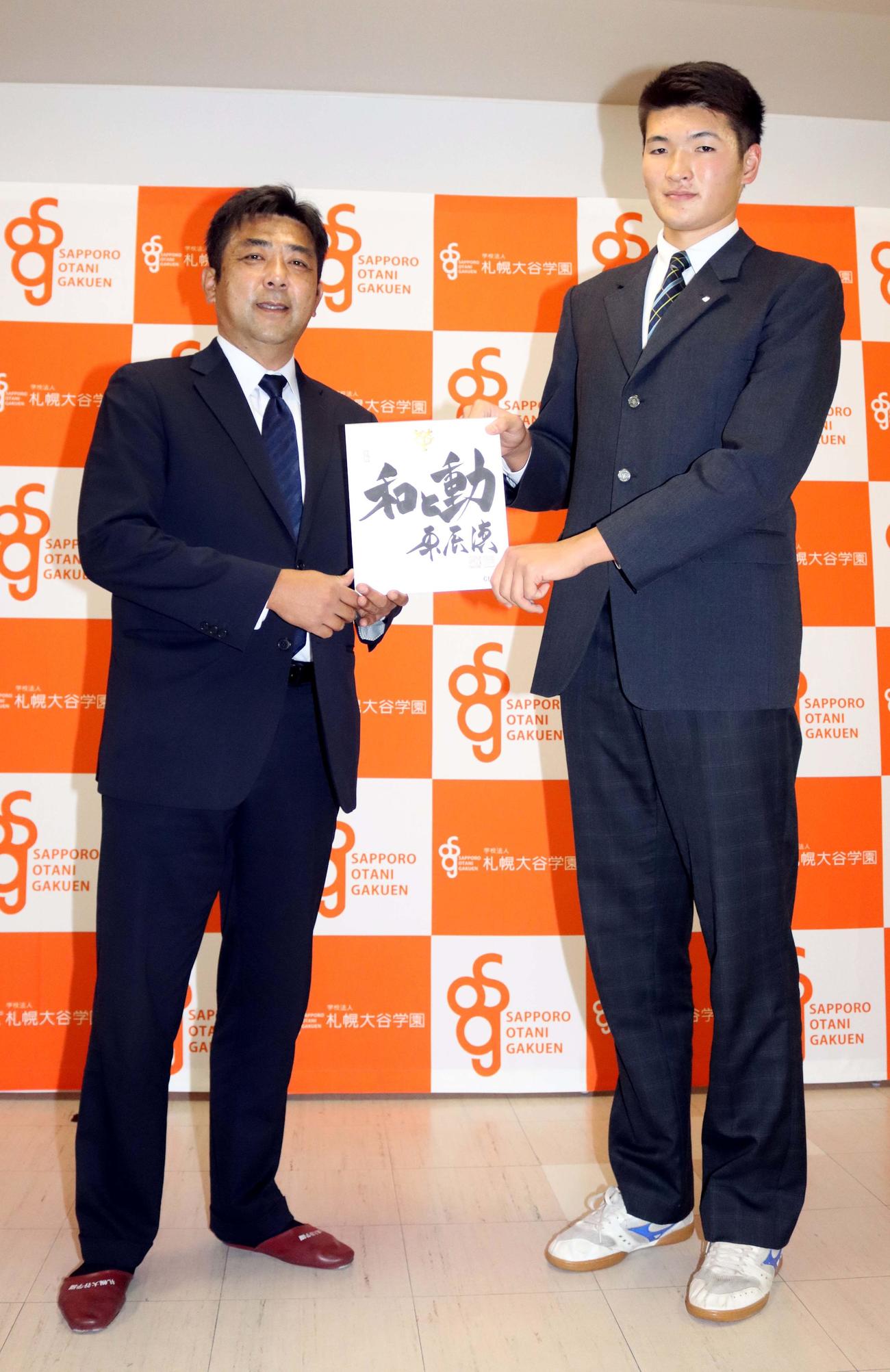 巨人の柏田スカウトから原監督直筆の書が書かれた色紙を渡される札幌大谷・阿部（右）（撮影・永野高輔）