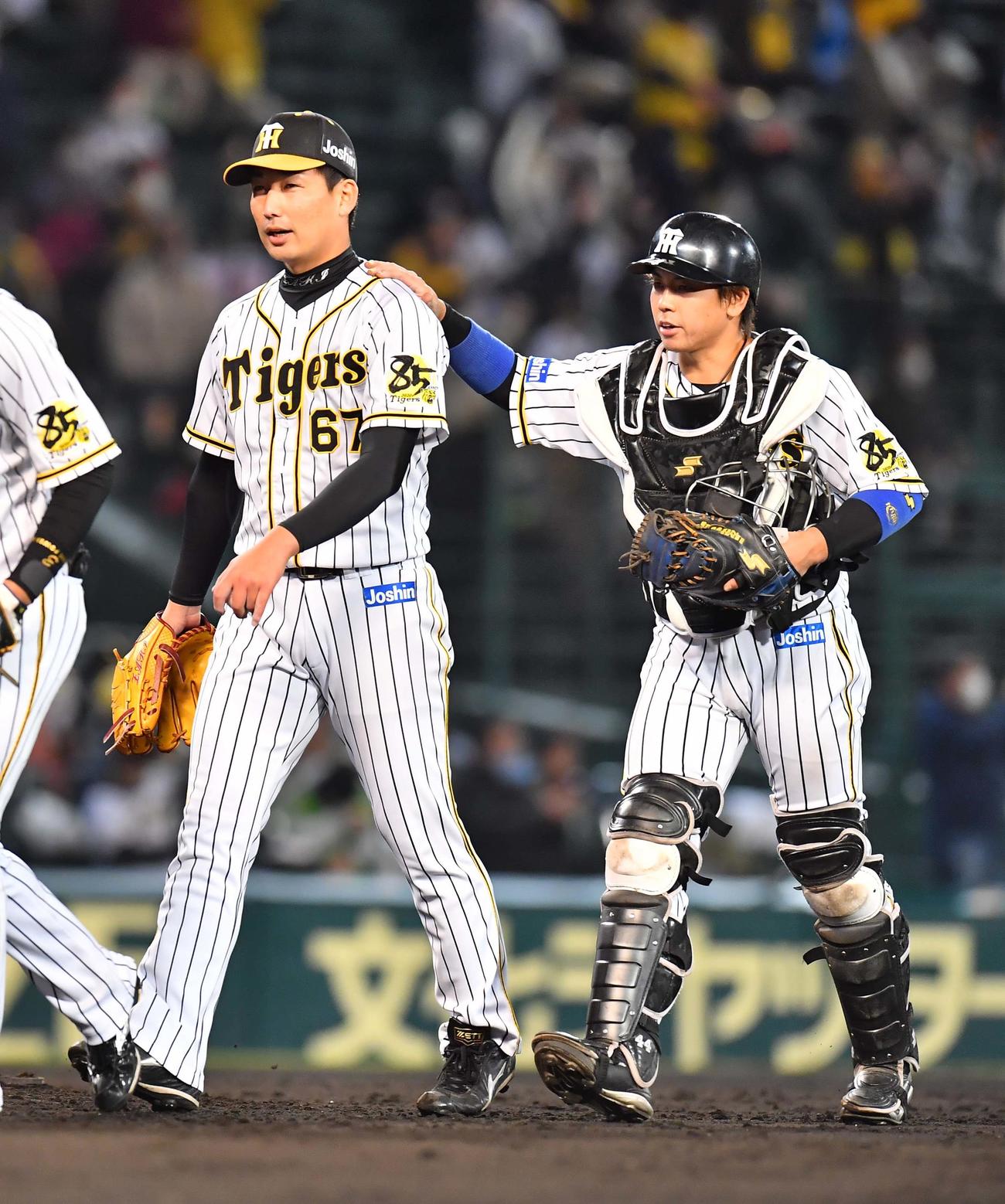 阪神対ヤクルト　ヤクルトに勝利しセーブをあげた岩崎の肩に手をやりグラウンドを引き揚げる梅野（撮影・上田博志）