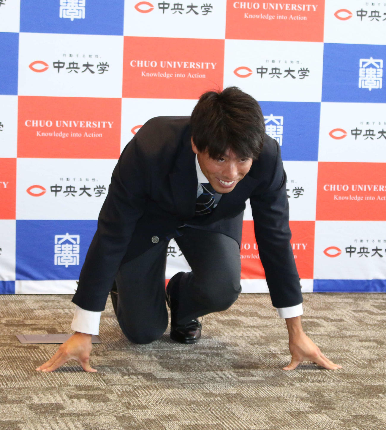 日本ハムから指名あいさつを受けたドラフト2位の中大・五十幡はクラウチングスタートの構えをして笑顔（撮影・木下大輔）