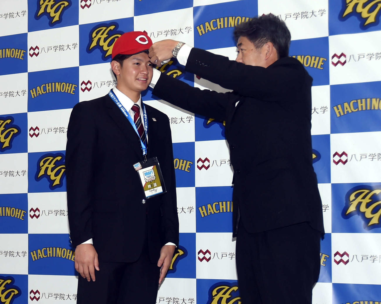 広島近藤スカウトに帽子をかぶらせてもらう八戸学院大・大道（左）（撮影・相沢孔志）