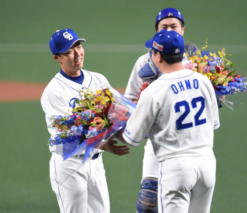 大野雄（右）から花束を受け取る吉見（撮影・森本幸一）