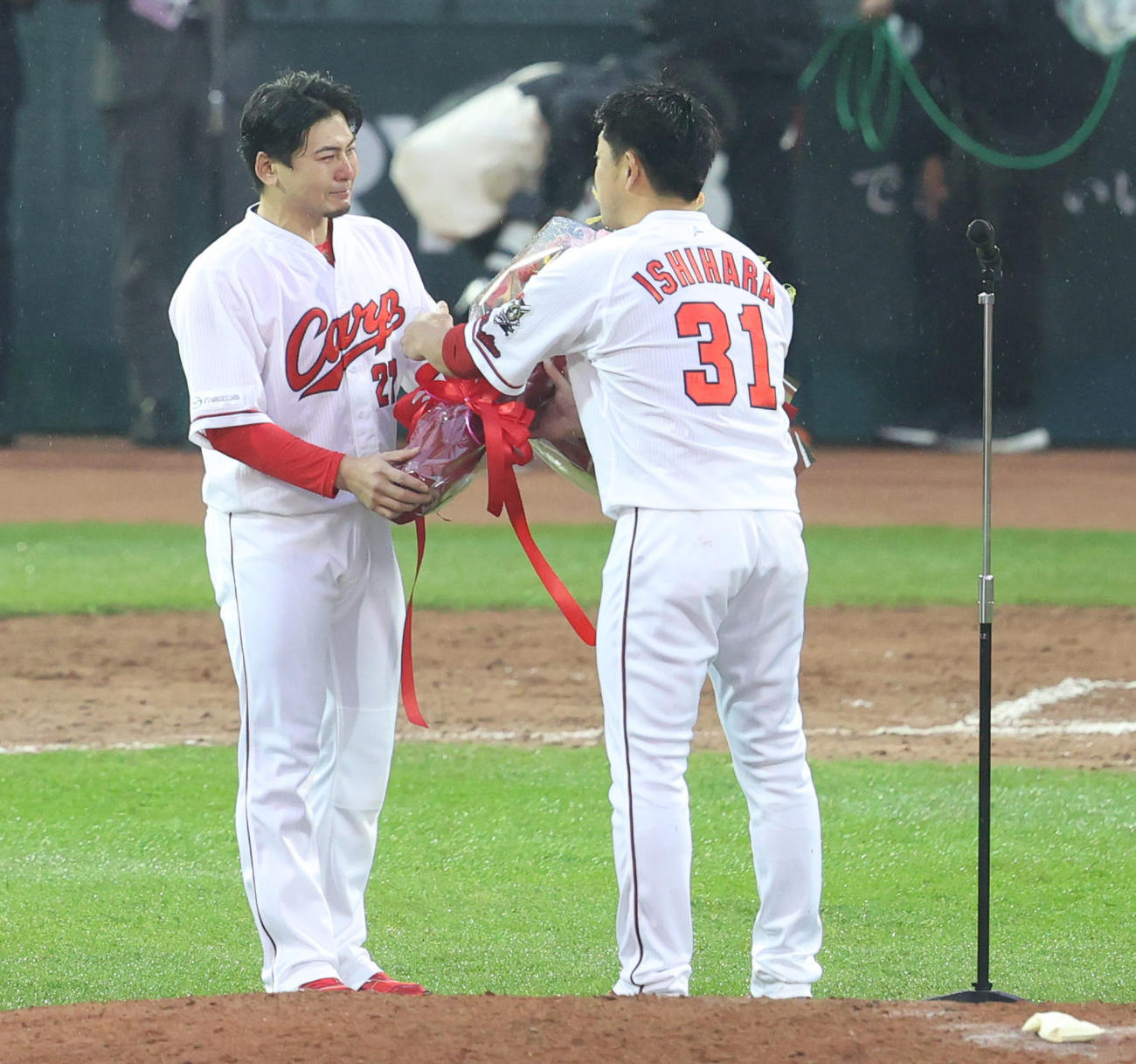 引退セレモニーで涙をみせる会沢翼（左）から花束を受け取る石原慶幸（撮影・清水貴仁）