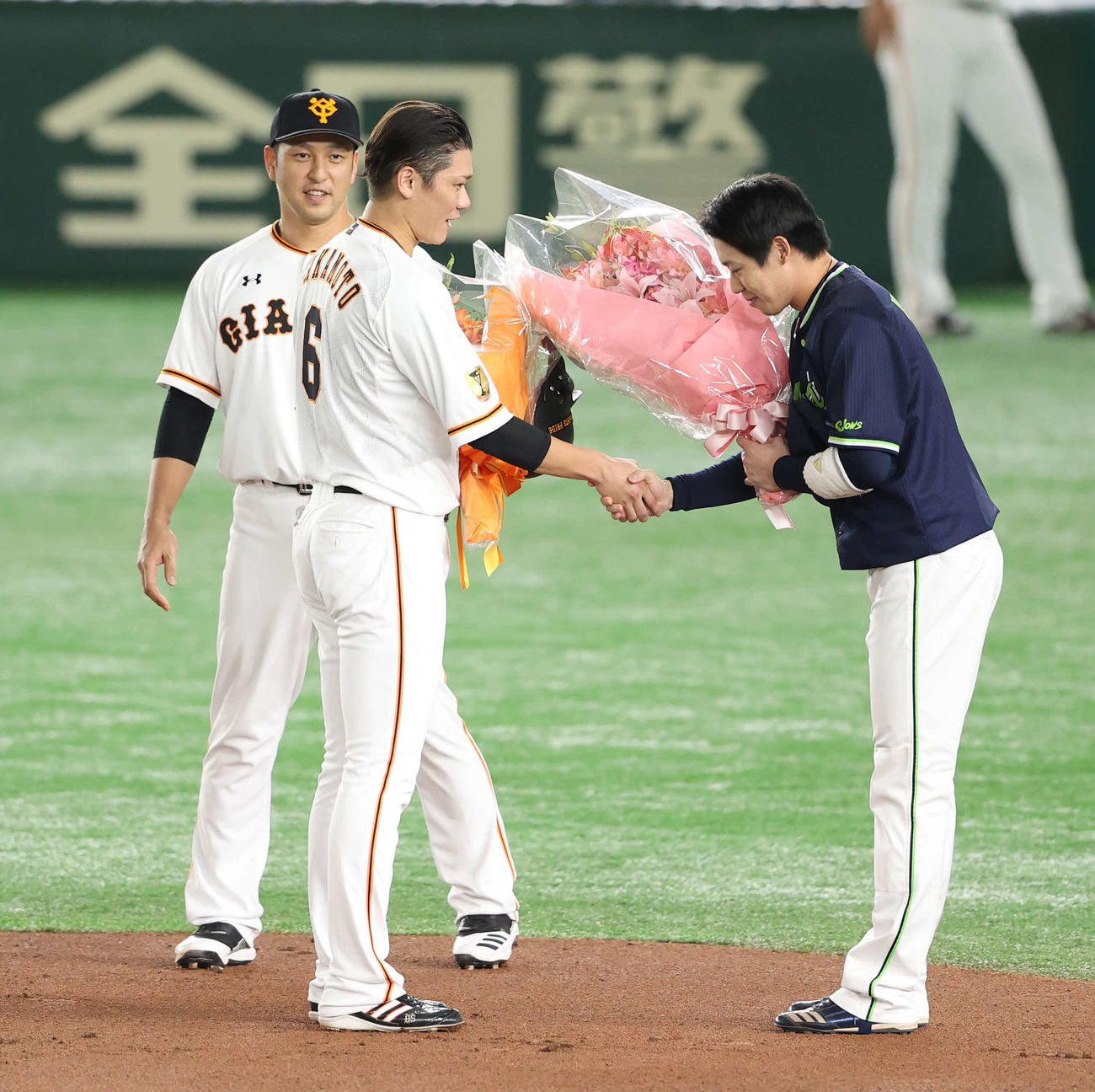 巨人対ヤクルト　1回裏巨人2死、プロ通算2000安打を達成した坂本（中央）と花束を手に握手を交わすヤクルト山田哲（右）。左は中島（撮影・河野匠）