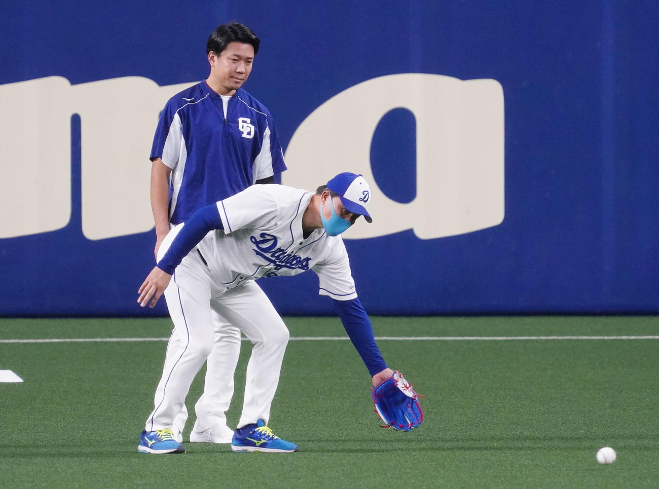 大野雄大（奥）と話をしている中、打撃練習のボールを捕球する与田剛監督（手前）奥は大野雄（撮影・森本幸一）
