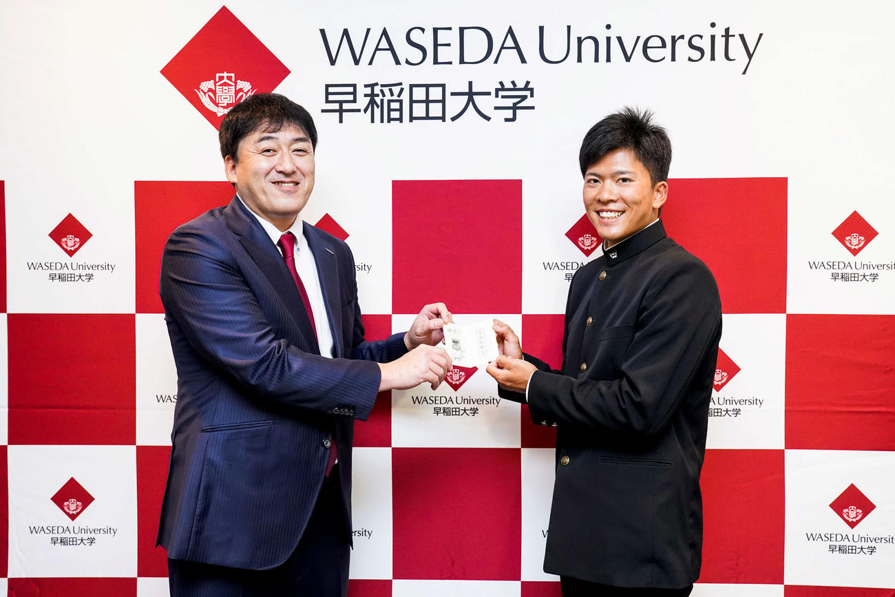 指名あいさつを受けた楽天ドラフト1位指名の早大・早川（右）は楽天石井GM（左）から「輝き放て！」と書かれた交渉権獲得の当たりくじを受け取る（球団提供）