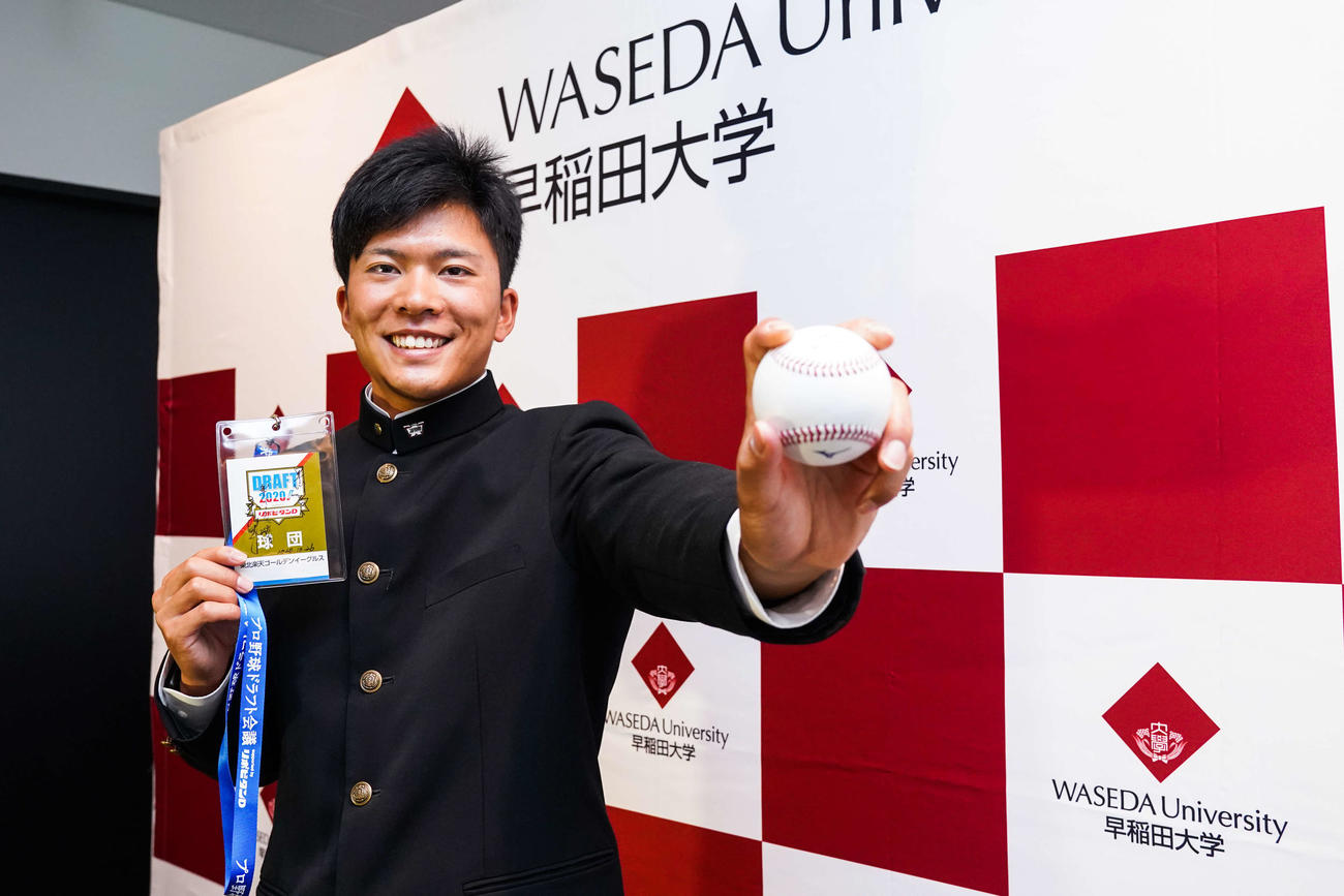 指名あいさつを受けた楽天ドラフト1位指名の早大・早川はドラフト会議のIDパスとボールを握り、笑顔を見せる（球団提供）