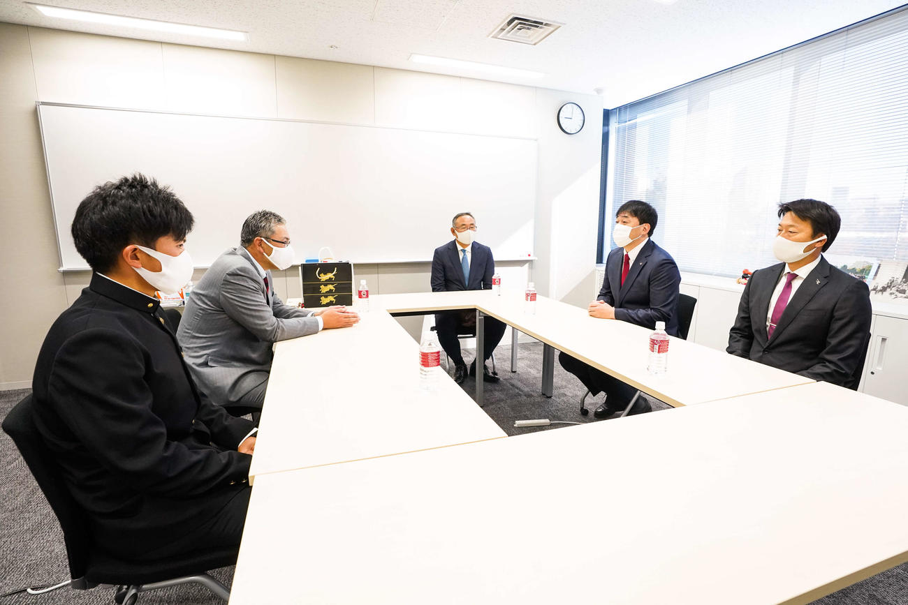 指名あいさつを受ける楽天ドラフト1位指名の早大・早川（手前左）。左奥は早大・小宮山監督、中央は楽天後関スカウト部長、右手前は沖原スカウト、右奥は楽天石井GM（球団提供）