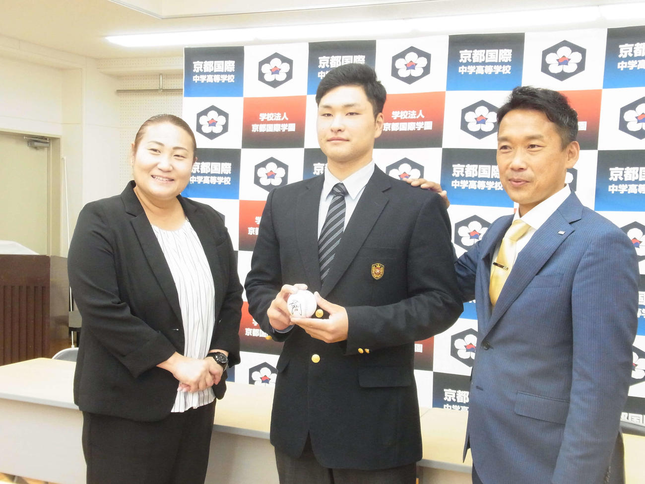 オリックスの育成ドラフト4位の京都国際・釣（中央）は、担当の下山スカウト（右）と乾スカウトから中嶋監督代行のサイン入りボールを贈られる（撮影・堀まどか）