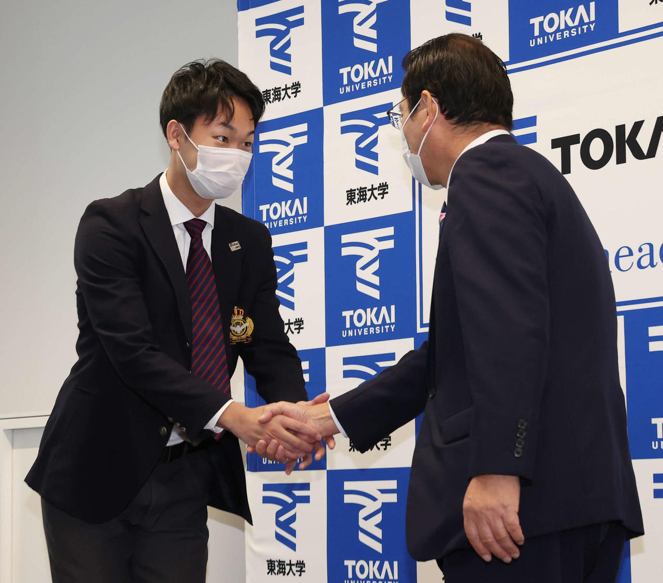 巨人ドラフト2位指名のあいさつで巨人大塚副代表（右）と握手する東海大・山崎（撮影・河野匠）