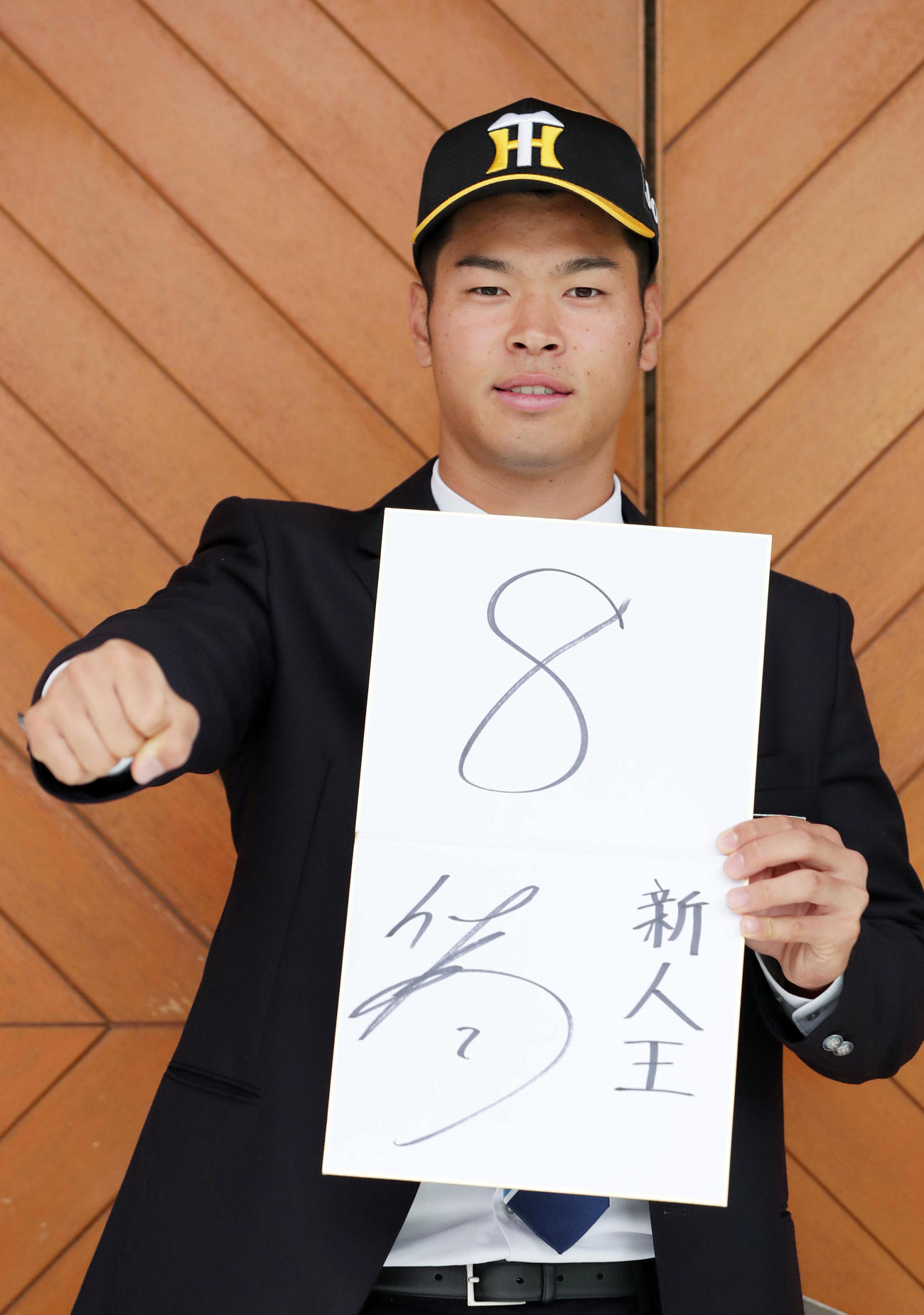 阪神との仮契約を終え、背番号「8」と目標の「新人王」と記した色紙を手にガッツポーズする近大・佐藤輝（撮影・前田充）