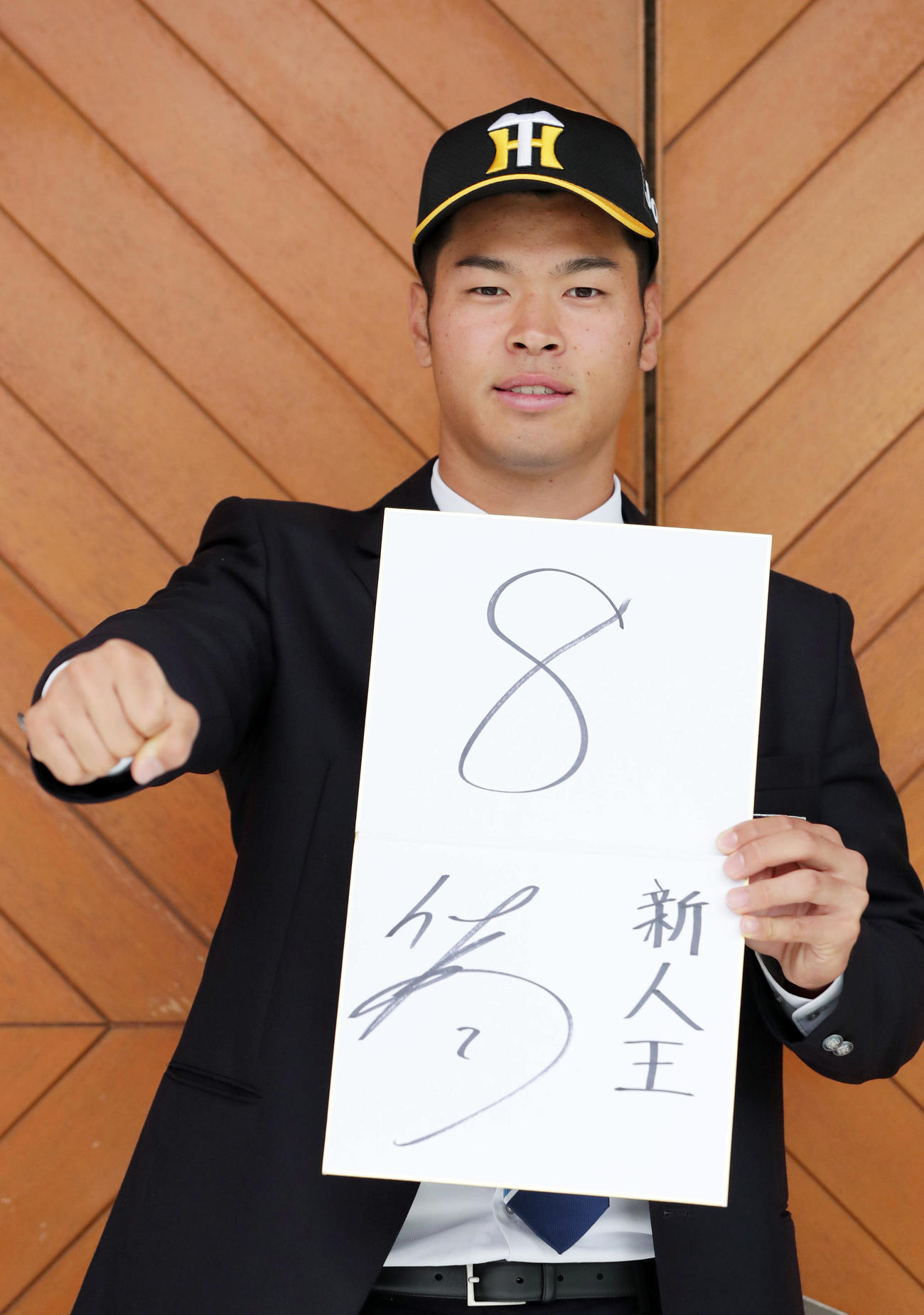 阪神との仮契約を終え、背番号「8」と目標の「新人王」と記した色紙を手にガッツポーズする近大・佐藤輝明（撮影・前田充）