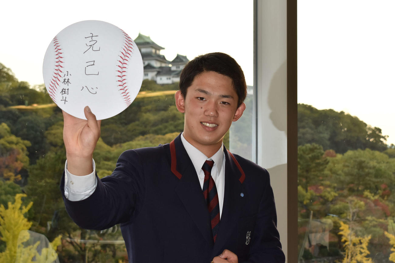 和歌山城をバックに、「克己心」と書いた色紙を掲げる広島ドラフト4位小林（撮影・古財稜明）