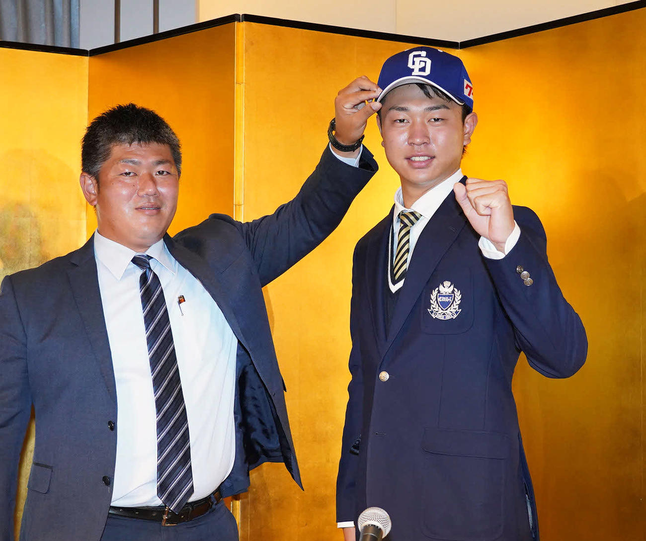 中日と仮契約を終え、会見後に清水スカウト（左）とポーズを決めるドラフト1位の高橋（撮影・森本幸一）