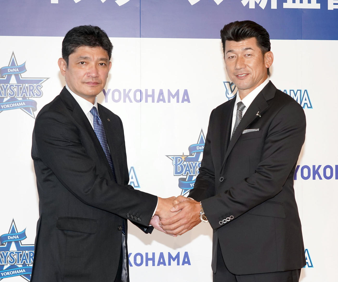 就任会見で三原一晃球団代表（左）と握手をかわすDeNA三浦新監督（代表撮影）